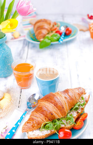 Köstliche Frühling Frühstück auf einem weißen Hintergrund. Strauß mit frischen Tulpen. Kleine und Große bunte Ostereier. Haferflocken, Kaffee, frischen Beeren. Stockfoto