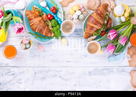 Frühstück für zwei. Croissants mit Salat und Espresso. Frische säfte und Süßigkeiten. Frühling Tulpen. Ostern Dekor. Weiß Holz- Hintergrund. Stockfoto