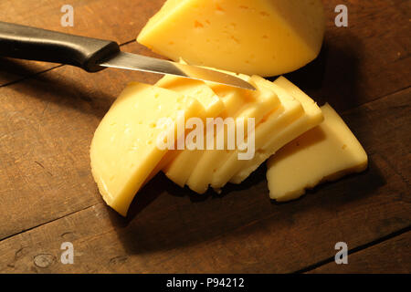 Schnittkäse und Messer liegen auf Holz- Hintergrund Stockfoto