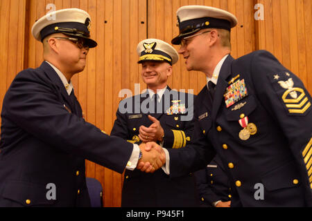 Coast Guard 13. Bezirk Master Chief Petty Officer Jason Wong, auf-kommenden command Master Chief, schüttelt Hände mit Master Chief Sean McPhilamy, die Ausrückenden command Master Chief nach Linderung McPhilamy während eines Change-of-watch Zeremonie in Seattle, 9. Juli 2018 statt. Wong und McPhilamy schüttelte Hände nach Abschluss der offiziellen Übertragung der Autorität. U.S. Coast Guard Foto von Petty Officer 3. Klasse Amanda Norcross. Stockfoto