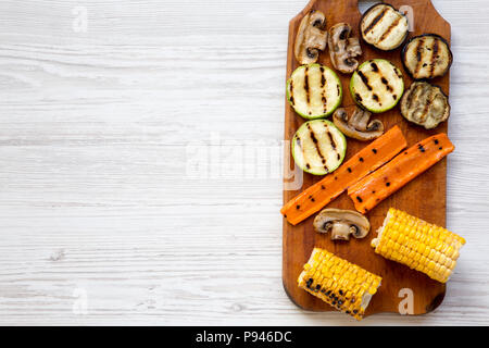 Gegrilltes Gemüse auf rustikalen Holzbrett auf weißem Holz- Hintergrund, Ansicht von oben. Von oben, flach und Overhead. Kopieren Sie Raum und Text. Stockfoto