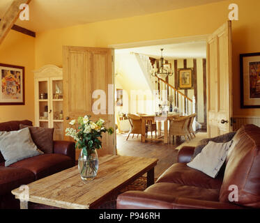 Braunen Ledersofas und rustikaler Couchtisch in Traditionelle, cremefarbene Land Wohnzimmer Stockfoto