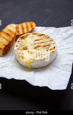 Gegrilltem Camembert Käse auf einem schwarzen Hintergrund, Seitenansicht. Close-up. Stockfoto