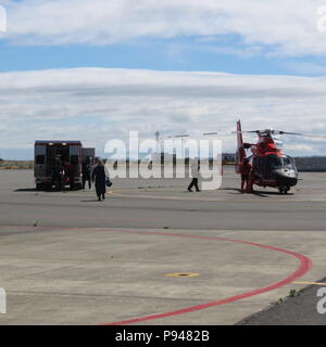 Ein Coast Guard helicopter aircrew von Air Station Port Angeles überträgt eine Systemblockierung zu lokalen Emergency Medical Service Personal nach ihm erholt sich das Wasser in der Nähe der Straße von Juan de Fuca am 10. Juli 2018. Der 73-jährige Mann hatte angeblich über Bord Kreuzfahrtschiff Seven Seas Mariner auf 4:30 Uhr morgens. (U.S. Coast Guard Foto.) Stockfoto