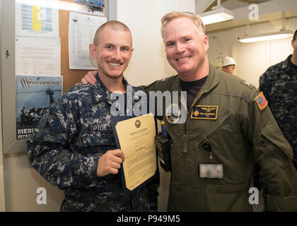 NORFOLK, Virginia (9. Juli 2018) Hospital Corpsman 2. Klasse Matthew Tipton, von Grau, Tennessee, auf USS Gerald R. Ford's (CVN 78) Medizinische Abteilung zugewiesen, erhält seine Ernennungsurkunde in den Rang eines Petty Officer Second class von Kapitän Richard McCormack, Ford's kommandierender Offizier. Tipton war nach seiner Auswahl für die verdienstvolle Förderung Programm gefördert. (U.S. Marine Foto von Mass Communication Specialist 2. Klasse Kristopher Ruiz) (Dieses Bild hat durch die Unschärfe Abzeichen für Zwecke der Sicherheit geändert wurde) Stockfoto