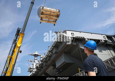 NORFOLK, Virginia (11. Juli 2018) Der Bootsmann Mate 3. Klasse Nicholas Soss, von Blissfield, Michigan, auf USS Gerald R. Ford's (CVN 78) deck Abteilung zugewiesen, beobachtet ein Off-load von MK-8 Rettungsinseln von Flight Deck des Schiffes. Ford ist derzeit die Werften für post Shake down Verfügbarkeit in Newport News, Virginia. (US Navy Foto von Mass Communication Specialist 2. Klasse Jason Pastrick/Freigegeben) Stockfoto