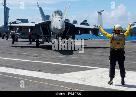 180713-N-OY 799-0171 philippinischen Meer (13. Juli 2018) der Luftfahrt Bootsmann Mate (Handling) 3. Klasse Akiyah Jordan von Pensacola, Fla., leitet ein Flugzeug auf dem Flugdeck der Marine vorwärts - bereitgestellt Flugzeugträger USS Ronald Reagan (CVN 76). Ronald Reagan, das Flaggschiff der Carrier Strike Group 5, bietet eine Bekämpfung bereit, Kraft, schützt und verteidigt die kollektive maritime Interessen seiner Verbündeten und Partnern in der indopazifischen Region. (U.S. Marine Foto von Mass Communication Specialist 2. Klasse Kenneth Abbate / freigegeben) Stockfoto