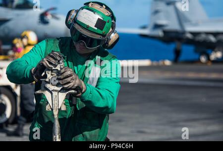 180712-N-OY 799-0014 philippinischen Meer (12. Juli 2018) der Luftfahrt Bootsmann Mate (Ausrüstung) Flieger John hilson, von Scranton, PA, inspiziert ein halten Zurück bar vor der Flugbetrieb auf dem Flugdeck der Marine vorwärts - bereitgestellt Flugzeugträger USS Ronald Reagan (CVN 76). Ronald Reagan, das Flaggschiff der Carrier Strike Group 5, bietet eine Bekämpfung bereit, Kraft, schützt und verteidigt die kollektive maritime Interessen seiner Verbündeten und Partnern in der indopazifischen Region. (U.S. Marine Foto von Mass Communication Specialist 2. Klasse Kenneth Abbate / freigegeben) Stockfoto