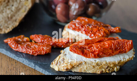 Bruschetta mit getrockneten Tomaten und Frischkäse mit Kochen von Oliven. Traditionelle italienische Küche Sandwich. Antipasti Stockfoto