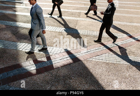 Männer Pendeln zum Büro morgens Durchführung Büro Taschen. Geschäftsleute in Eile, Büro zu Fuß auf Stadt Straße mit einigen mit ihren mobil erreichen. Stockfoto