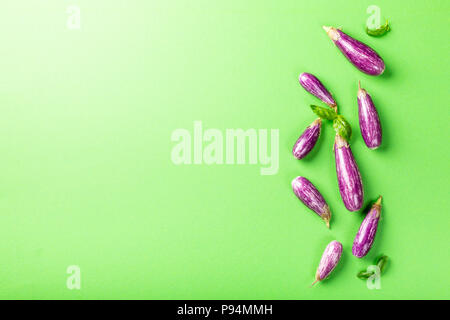 Haufen kleine Aubergine oder Aubergine Gemüse mit basilikumblätter auf grünem Hintergrund. Gesunde Ernährung Konzept mit kopieren. Stockfoto