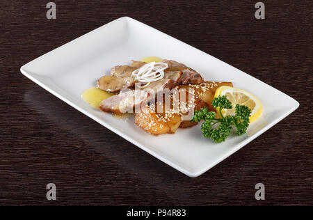 Brocken Fleisch mit Sauce, Bratkartoffeln und einer Scheibe Zitrone und Petersilie auf weiße Platte. Europäische Küche. Seitenansicht Stockfoto