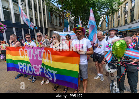 London, Großbritannien. 14. Juli 2018. Croydon Stolz Stuhl Paula Goodwin ist in der Mitte des Banners an der Vorderseite des Croydon Stolz Prozession. Mehrere hundert Menschen Parade durch das Zentrum von Croydon auf dem Weg in das dritte Croydon Croydon Pridefest, durch Rat gefördert, in Wandle Park. Viele wurden in Buntes Kleid und es gab Banner, Fahnen, Schilder, Plakate und Einhörner. Das kostenlose Festival sollen LGBT + Gleichheit und Vielfalt in Croydon, zu fördern, und ist Londons zweitgrößte Pride Festival. Nach der Unterbrechung durch Anti-Trans-Aktivisten in London Pride, der Parade gab den Trans Peop Stockfoto