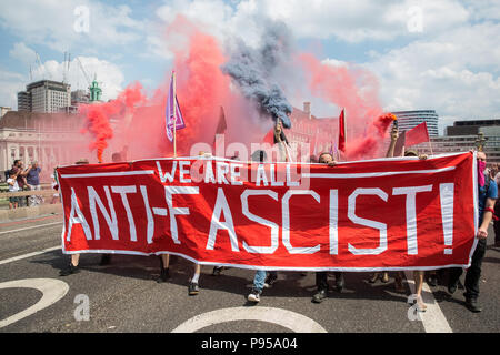 London, Großbritannien. 14. Juli 2018. Antifaschisten halten Rauch Granaten wie Sie März über die Westminster Bridge der rechtsextremen "Freien Tommy' (Robinson) und Trump Anhänger '' Willkommen Märsche Trump' zu erheben. Es gab einige Auseinandersetzungen, wie die anti-faschistischen März wurde von Freien Tommy Anhänger am Rande des Parliament Square angegriffen. Credit: Mark Kerrison/Alamy leben Nachrichten Stockfoto