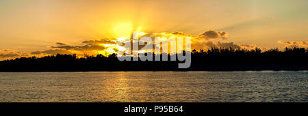 Ein spektakulärer Panoramablick goldfarbenen Sonnenaufgang seascape mit kräftigen Sonnenstrahlen (Sonne Strahlen) über Meer Wasser mit Wasser Reflexionen Stockfoto