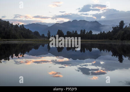Trees and mountains reflecting on a still lake, Lake Matheson, New Zealand Stockfoto