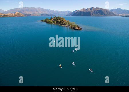 Antenne up Paddle Boarder paddeln zu Ruby Insel am Lake Wanaka, Neuseeland stand Stockfoto