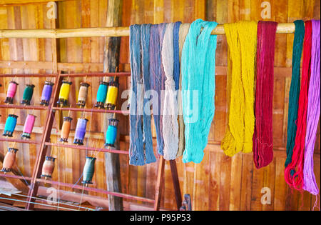 Die handgefärbten Garnen aus Baumwolle und Lotus trocknet auf dem hölzernen Pfosten in texile Workshop von Inpawkhon Dorf, Inle Lake, Myanmar. Stockfoto