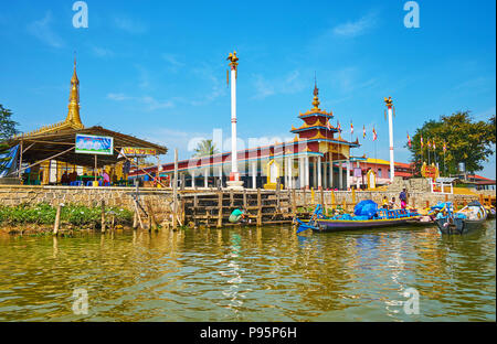 YWAMA, MYANMAR - 18. FEBRUAR 2018: Die Fassade des buddhistischen Klosters Tor mit zwei Säulen auf beiden Seiten, Kanus Schwimmer an der Wharf am Gate, auf F Stockfoto