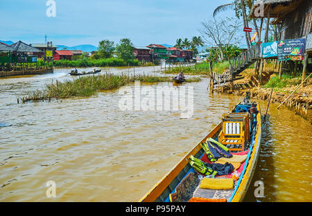 YWAMA, MYANMAR - 18. FEBRUAR 2018: Die bunten Häuser des Dorfes am Inle See mit zahlreichen Kanu Boote, schwebenden am Wasser entlang Straßen, auf Stockfoto