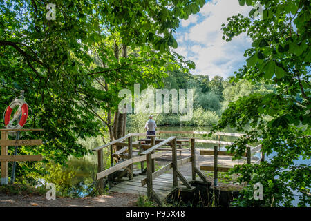 Mann angeln in der City Park entlang der Fluss Motala in Norrköping. Norrköping ist eine historische Stadt in Schweden. Stockfoto