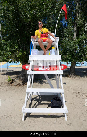 Rettungsschwimmer sitzen an seinem Beobachtungsposten auf einem Strand und Badegäste. Juni 12, 2018. Kiew, Ukraine Stockfoto