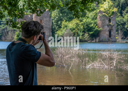 Mann mit einer Nikon DSLR-Kamera schießen die ertrunken 15. Jahrhundert Ruinen von Chateau Grandval, Royal, Frankreich. Stockfoto