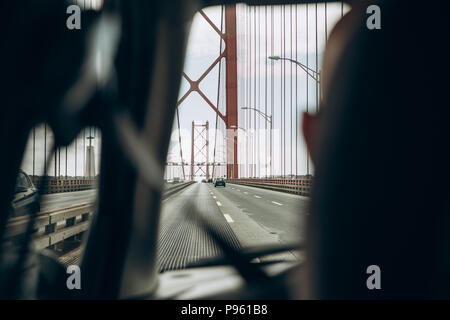 Blick aus dem Auto. Der Fahrer fährt über die Brücke, 25. April in Lissabon in Portugal. Anreise mit dem Auto oder eine Fahrt mit einem persönlichen täglichen Bus Stockfoto