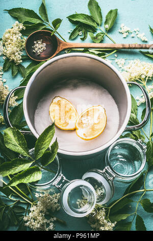 Zutaten für saisonale traditionelle Herstellung von Sirup oder Marmelade von holunder Blüten: Kochtopf, Löffel aus Holz, Zucker, Zitrone und Gläsern, Ansicht von oben Stockfoto