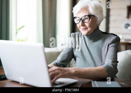 Ältere Frau, die Eingabe auf laptop Stockfoto