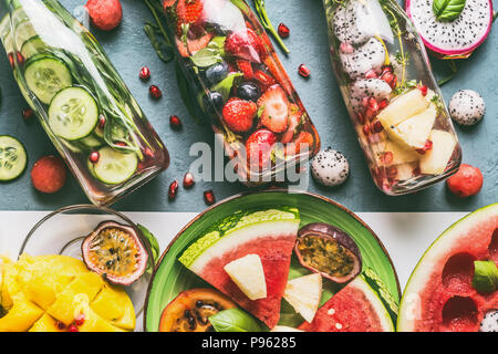 Verschiedenen bunten infundiert Wasser in Flaschen mit Früchten, Beeren, Gurken, Kräuter mit Zutaten auf den Tisch Hintergrund, Ansicht von oben. Lecker Sommer sauber beve Stockfoto