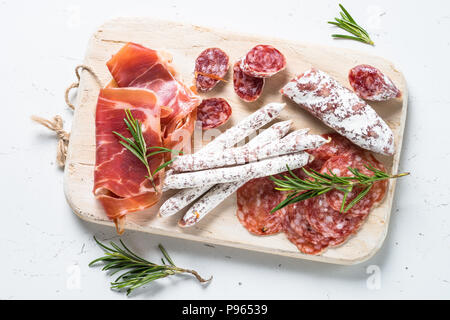 Antipasti. Traditionelle italienische Antipasti, geschnittenes Fleisch, Vorspeisen auf Holz Schneidebrett auf weißem Tabelle, Ansicht von oben. Stockfoto