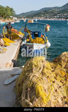 Fischer und Fischernetze auf der North Harbour Quay in Vathy Hafen mit der Stadt Vathy im Hintergrund. Auf der Insel Ithaka, Ionische Meer, G Stockfoto