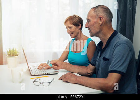 Senior Paar mit Laptop für Internet Shopping und Zahlungen zu Hause Stockfoto