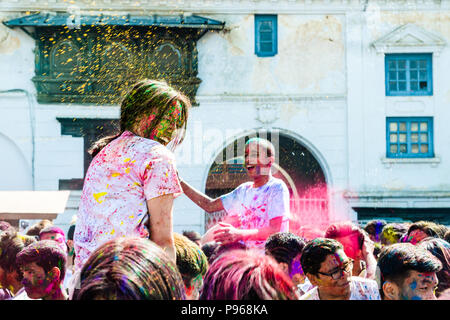 Die Menschen werfen Farbpigmente während Hindu Holi Festival der Farben feiern Basantapur Durbar Square in Kathmandu, Nepal Stockfoto