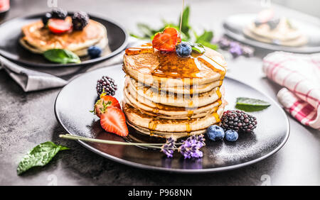 Pfannkuchen mit Erdbeeren Brombeeren Heidelbeeren lavendel Minze und Ahornsirup. Stockfoto