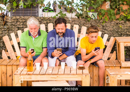 Familie Generationen Männer mit Großvater, Vater und Sohn, Neffe von Alt bis Jung bleiben zusammen mit Mobilfunktechnologie Smartphone eine Verbindung zu Inter Stockfoto