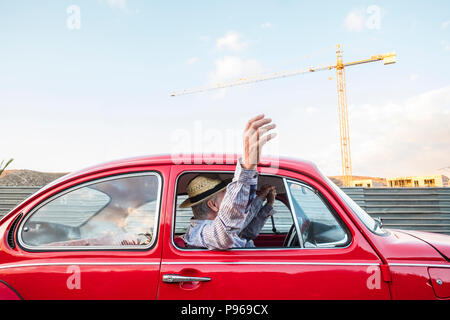 Kaukasische reifes Paar reisen und Fahren auf einem roten Oldtimer. Ferienhäuser und wonderlust concpet für glückliche Menschen, die auf der ganzen Welt. home Gebäude Stockfoto