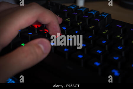 Gaming Keyboard mit rgb Beleuchtung Kerl in seine Hand im Gaming position Fokus Stockfoto