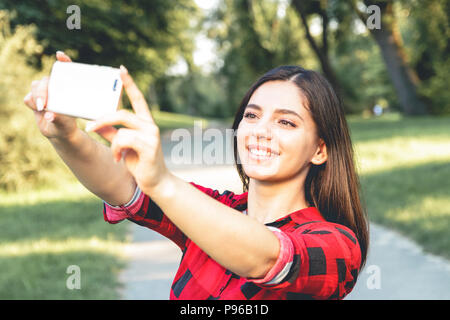 Porträt einer schöne Brünette Mädchen in einem roten, Plaid Shirt, wobei selfie, Video-Chats Stockfoto