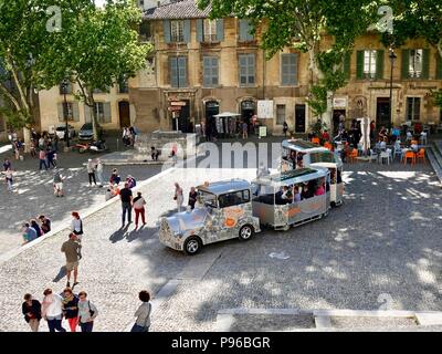 Der kleine touristische Zug zusammen mit ourists um den sehr großen Platz vor dem Palast des Papstes, des Palais des Papes, Avignon, Frankreich verstreut Stockfoto