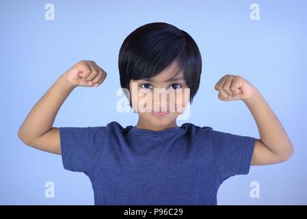 Portrait der Junge lächelte Kamera schaut. Smart Kid seine Arme Muskeln zeigen, mit den Fäusten Stockfoto