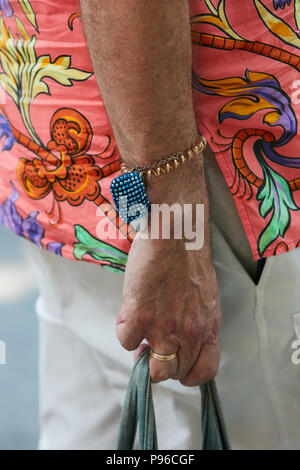 Mailand - Juni 18: der Mann mit den goldenen Armband mit blauem Glitter detail und orange Shirt mit Blumenschmuck vor Giorgio Armani Fashion Show, Mailand F Stockfoto