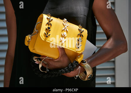 Mailand - Juni 18: Frau mit gelbem Leder Tasche mit schwarzen und weißen Dekorationen und goldenes Armband vor Giorgio Armani Modenschau, Milan Mode Stockfoto