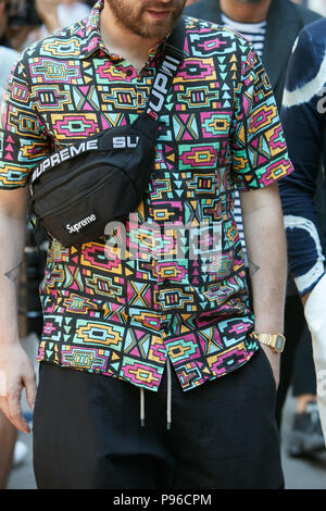 Mailand - Juni 18: Mann mit Obersten schwarzen Tasche und geometrischen Design T-Shirt in Gelb, Rosa, Türkis und schwarz Farben vor dem Fendi fashion show, Mailand Stockfoto