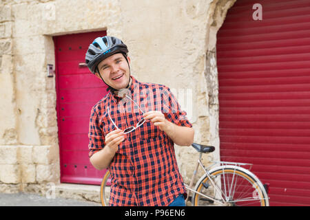 Radfahrer mit Sonnenbrille auf dem Hintergrund Bowlingbahn und Fahrradverleih Stockfoto