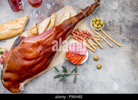 Ganzes Bein Schinken Jamón Serrano und Rose Wein auf grauem Hintergrund. Ansicht von oben. Flach. Stockfoto
