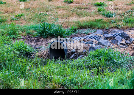 Überlauf Wasser Abfluss Rohr, die sich aus der grünen Grasboden Stockfoto