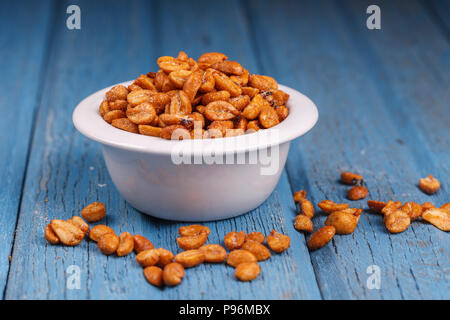 Ein studio Bild von gerösteten Erdnüssen in einer Schüssel mit etwas Verschütten über. Stockfoto