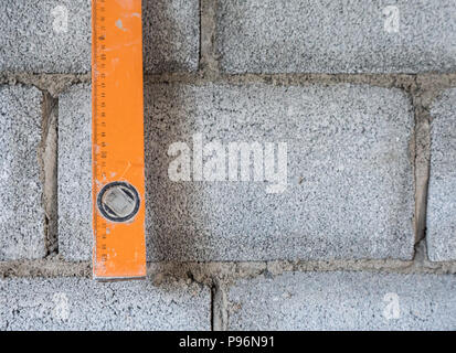 Schmutzige ebene Herrscher hängt in der Nähe der Mauer nach Maß in das unfertige Haus. Stockfoto